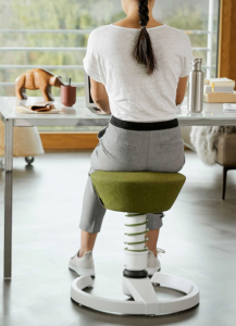 aeris Swopper (weißes Gestell und grüner Sitz) im Büro mit einer Frau